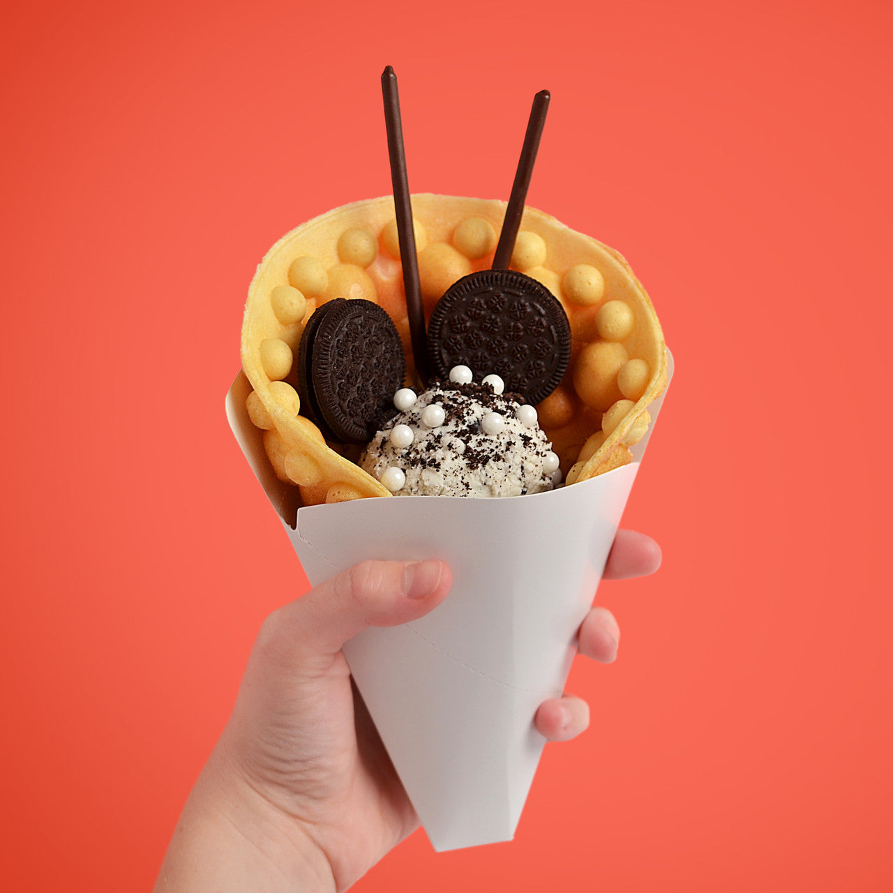 Paper Cones for Bubble Waffles, White, shown with bubble waffle inside and cookies and cream filling held by hand BWPC-10W Select Brands